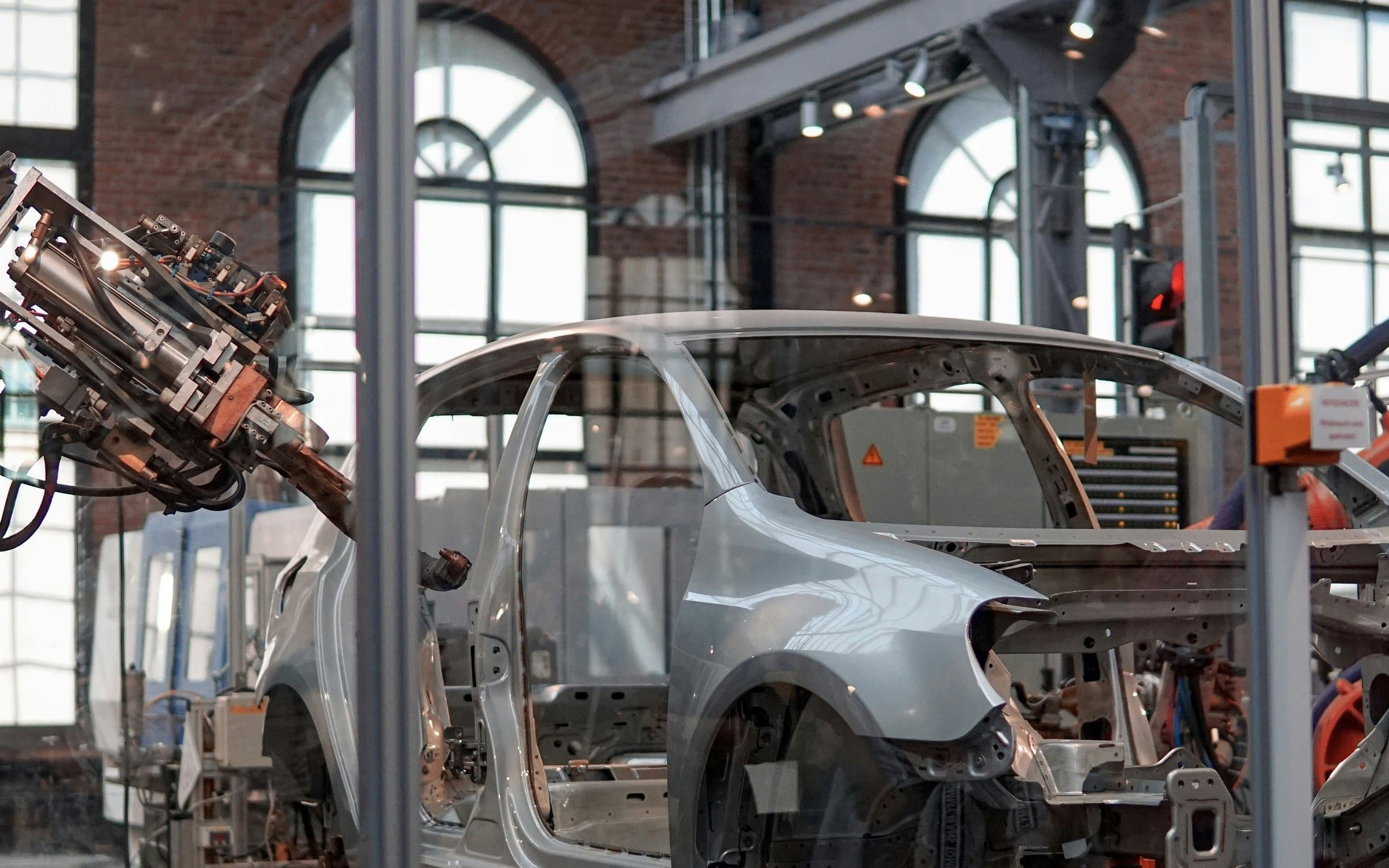 Car body-in-white on an automated welding line, with a robotic spot-welding gun