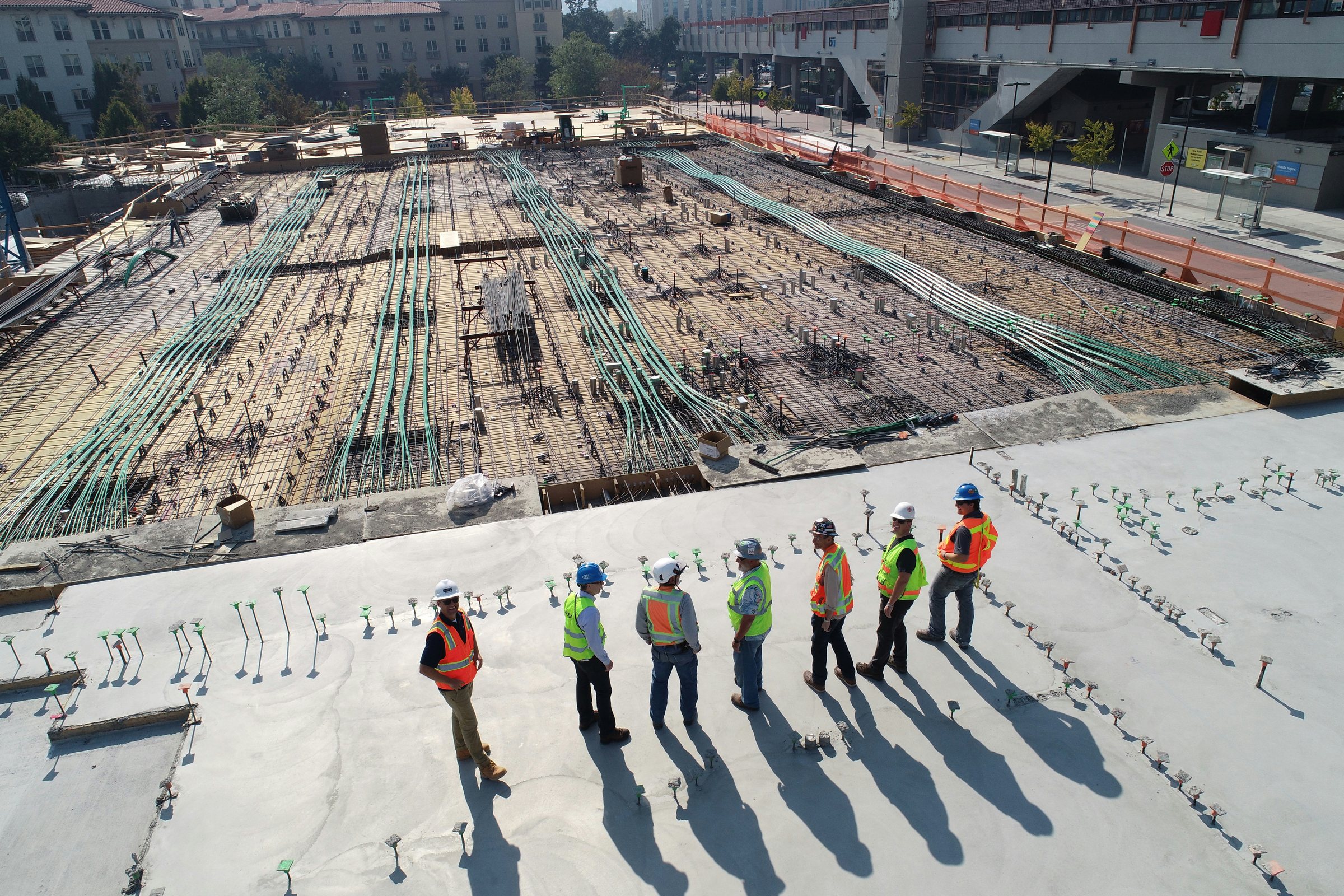 Site team on a concrete deck overlooking reinforcement and post-tensioning on a building site
