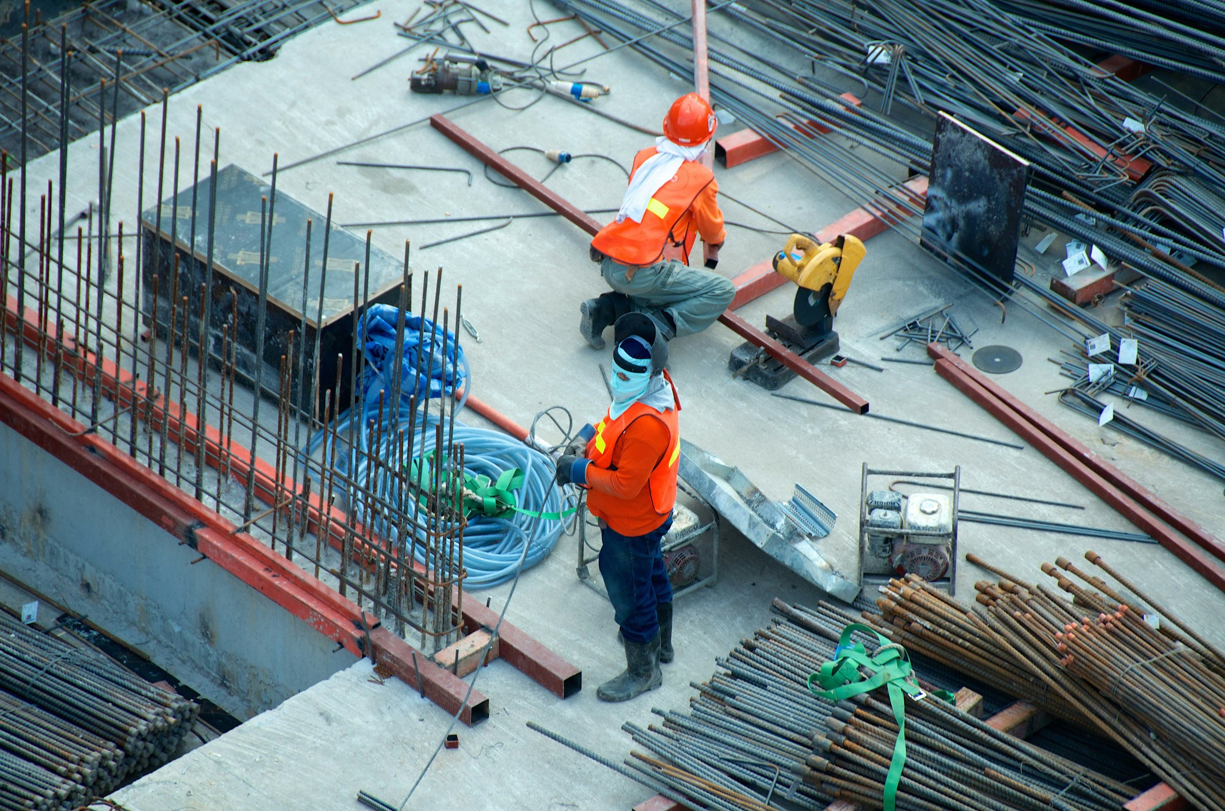 Construction crew working on a reinforced-concrete deck among rebar and site equipment