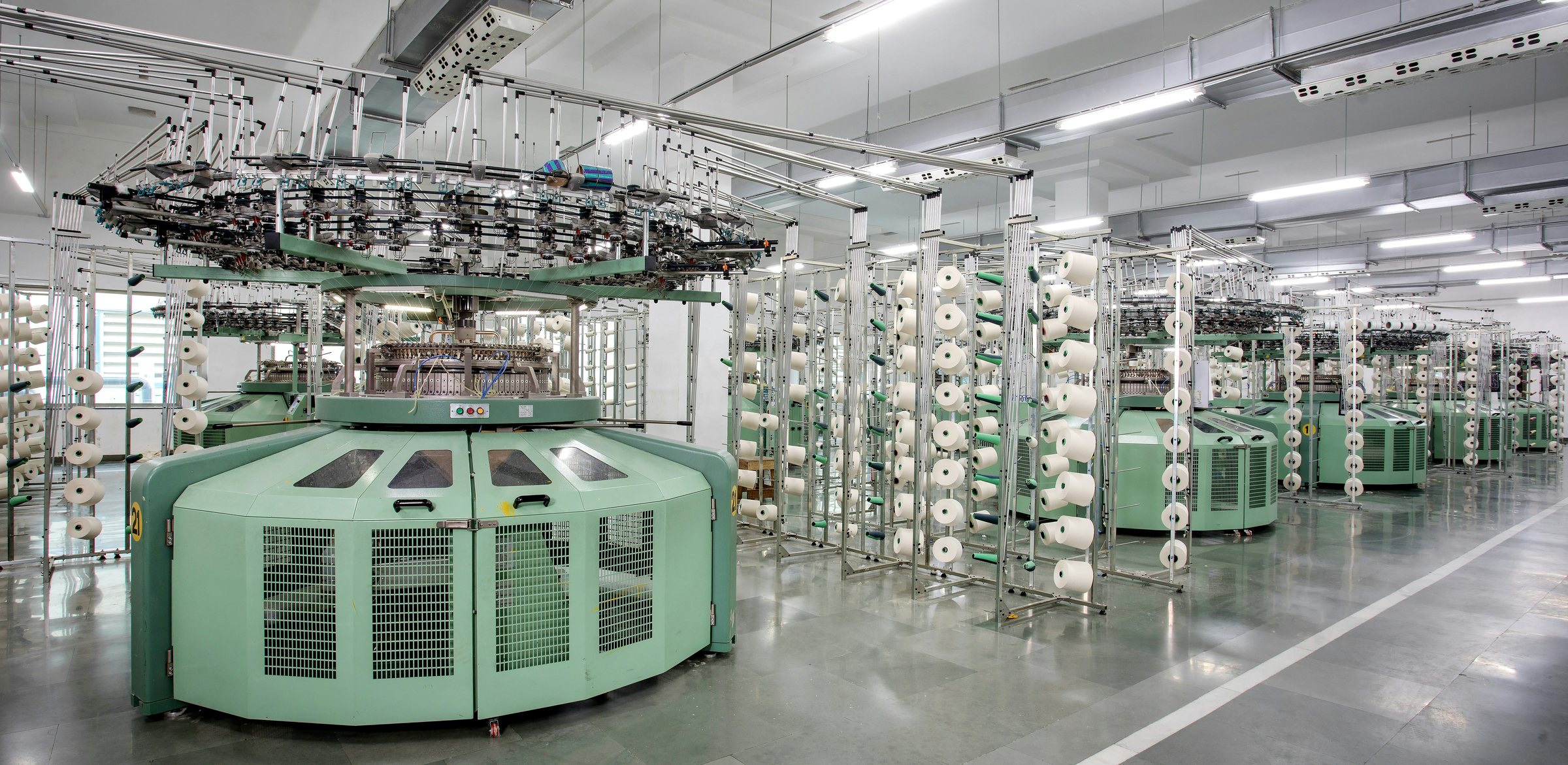 Circular knitting machines and yarn creels in a bright textile mill